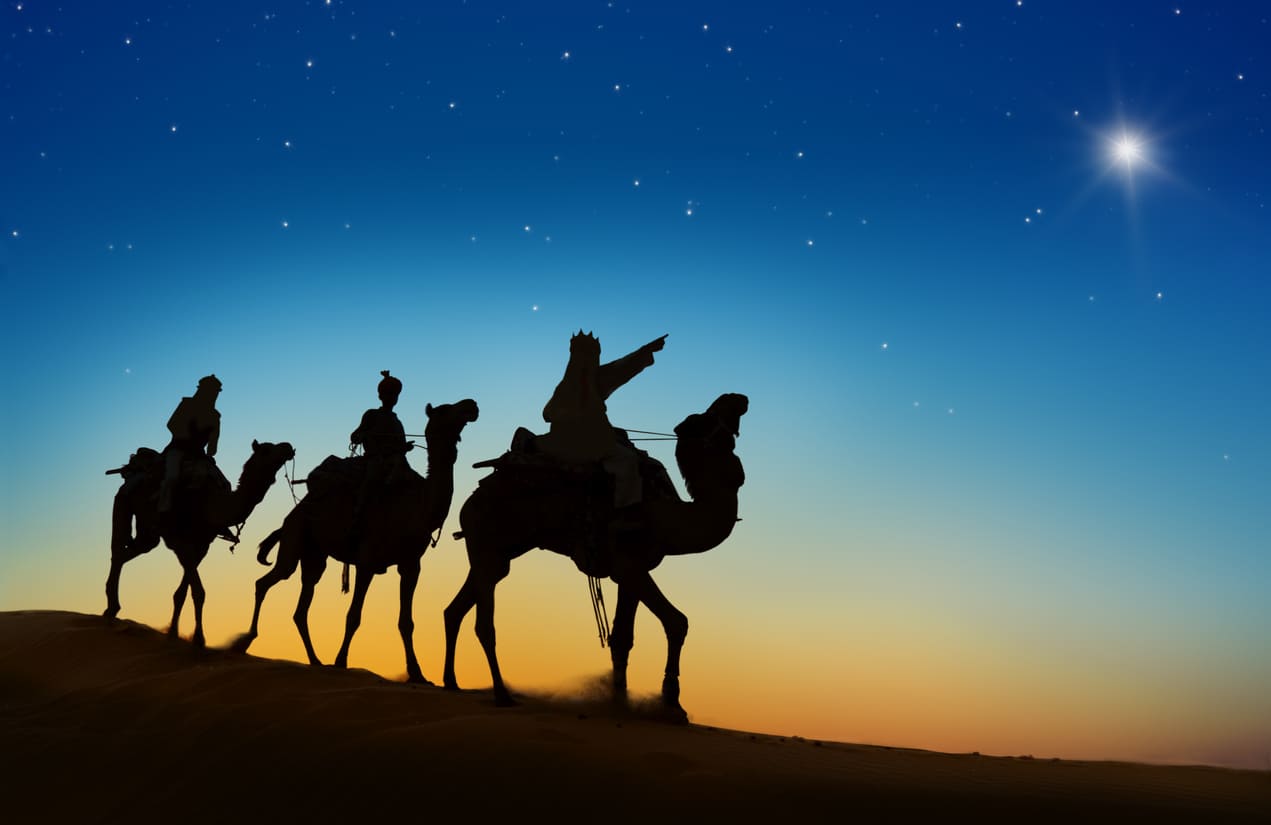 Three Wise Men on camels journey under a starlit sky, guided by the Star of Bethlehem.