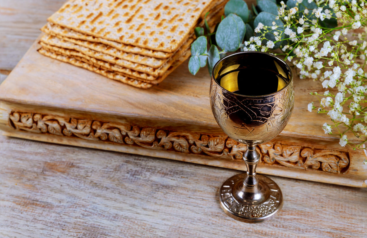 A beautifully arranged Passover scene featuring stacked matzah, a decorative wine cup, and flowers.