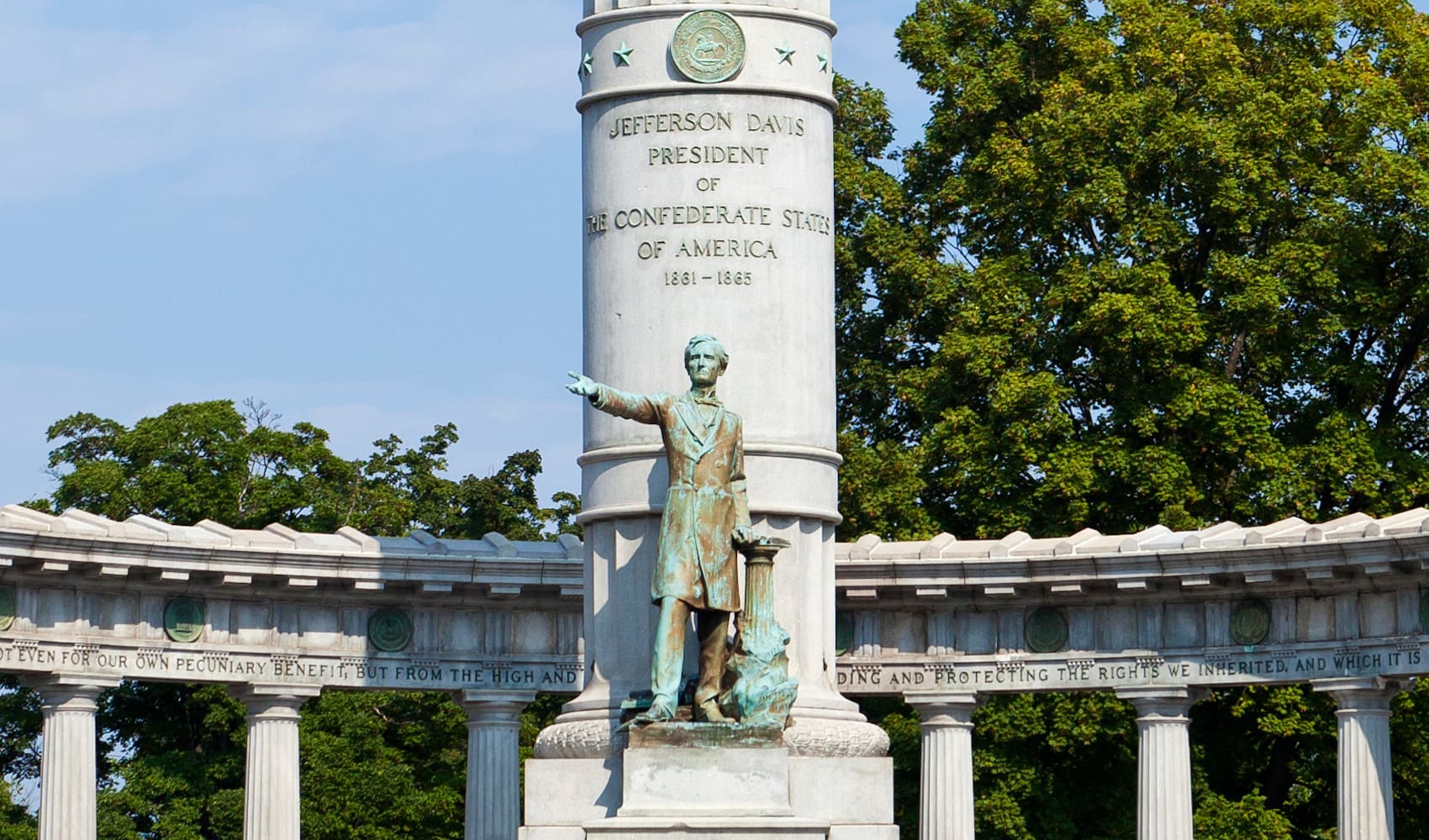 A statue of Jefferson Davis stands before a memorial column.