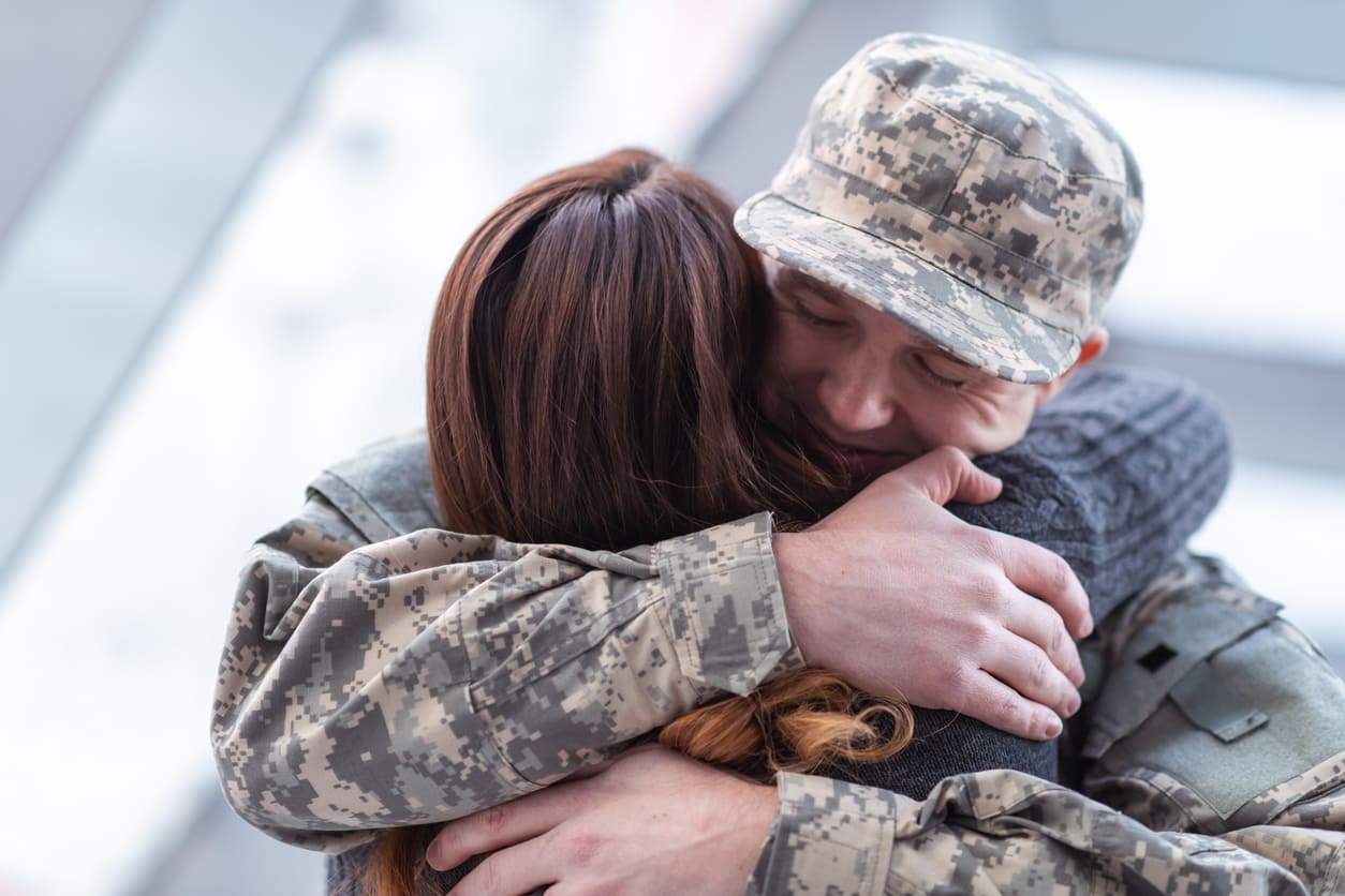 A soldier embraces their spouse in an emotional moment, symbolizing love, sacrifice, and unwavering support.