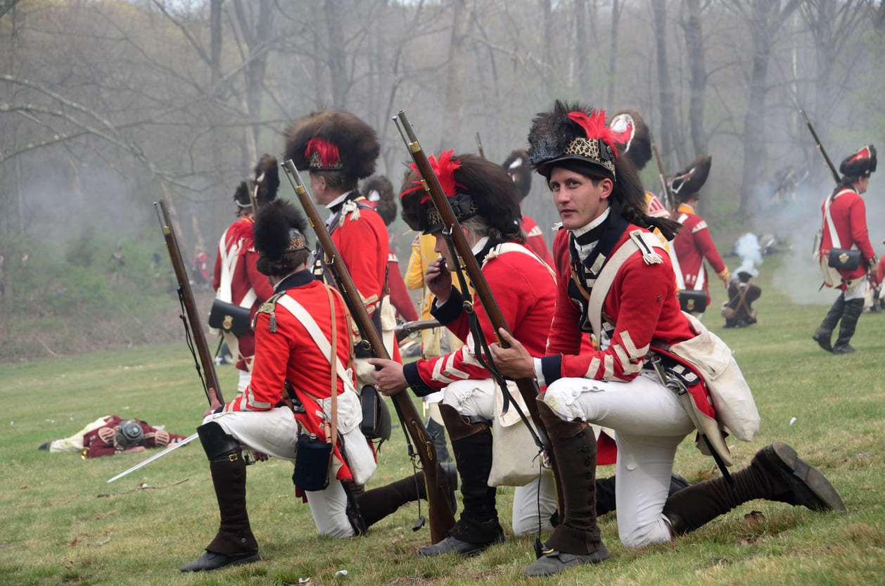 Actors in British Redcoat uniforms reenact a Revolutionary War scene on Patriots' Day.