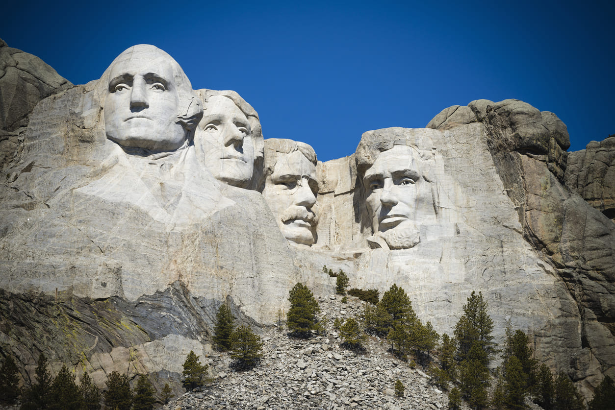 Mount Rushmore showcases the monumental carvings of Presidents Washington, Jefferson, Roosevelt, and Lincoln against a clear blue sky.