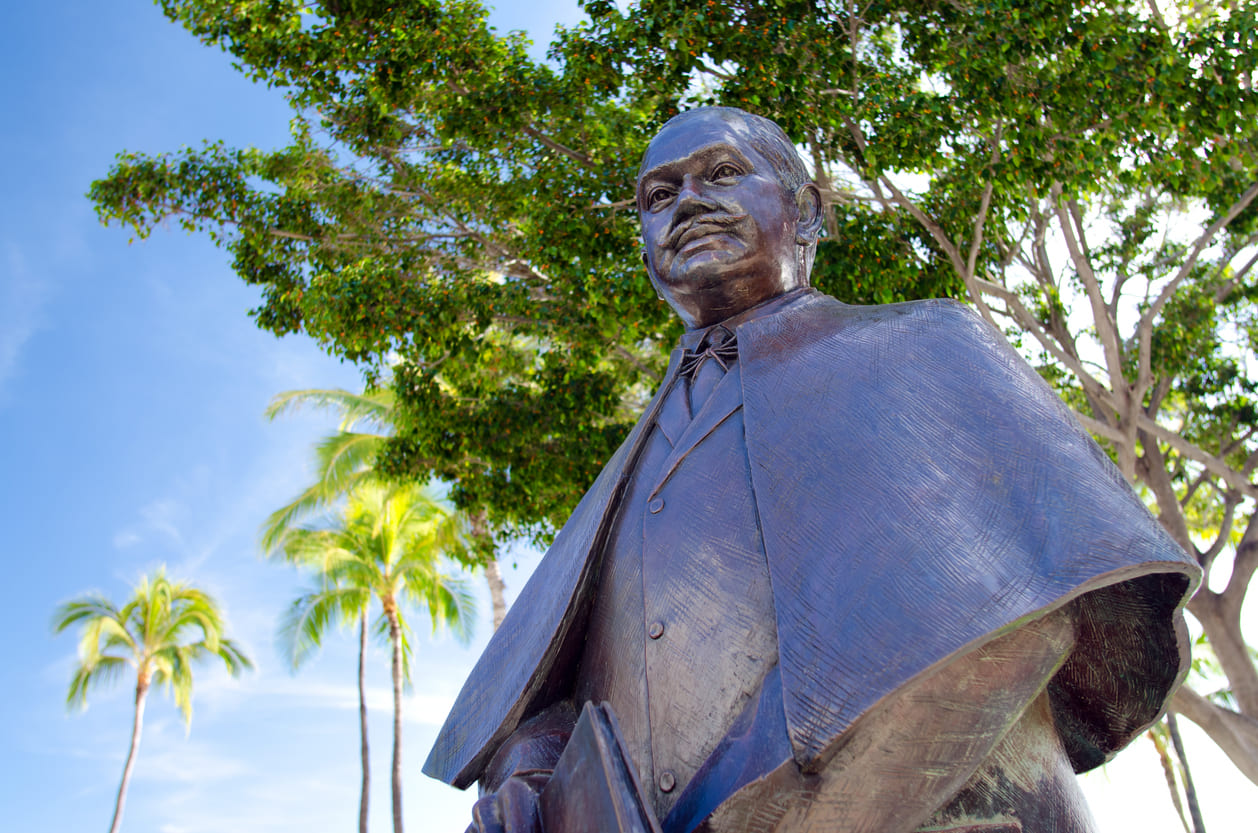 Statue of Prince Jonah Kuhio Kalanianaole under a bright blue sky.