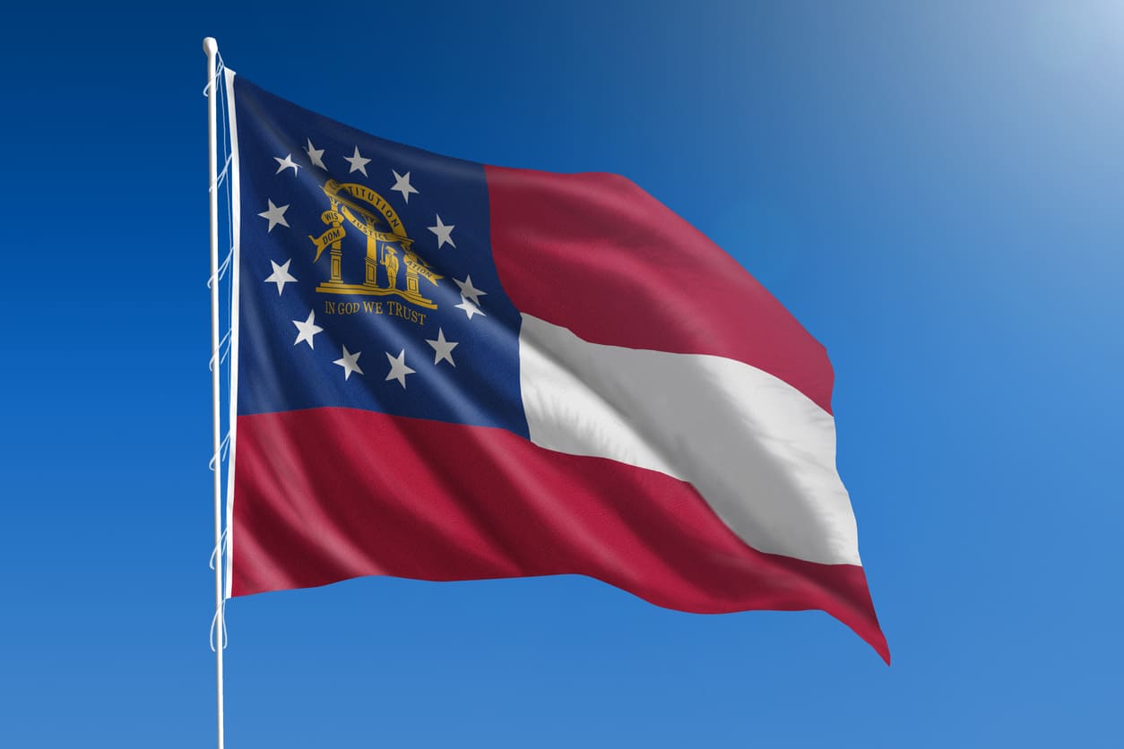 A vibrant Georgia state flag fluttering against a clear blue sky, symbolizing the state's heritage and neutrality.