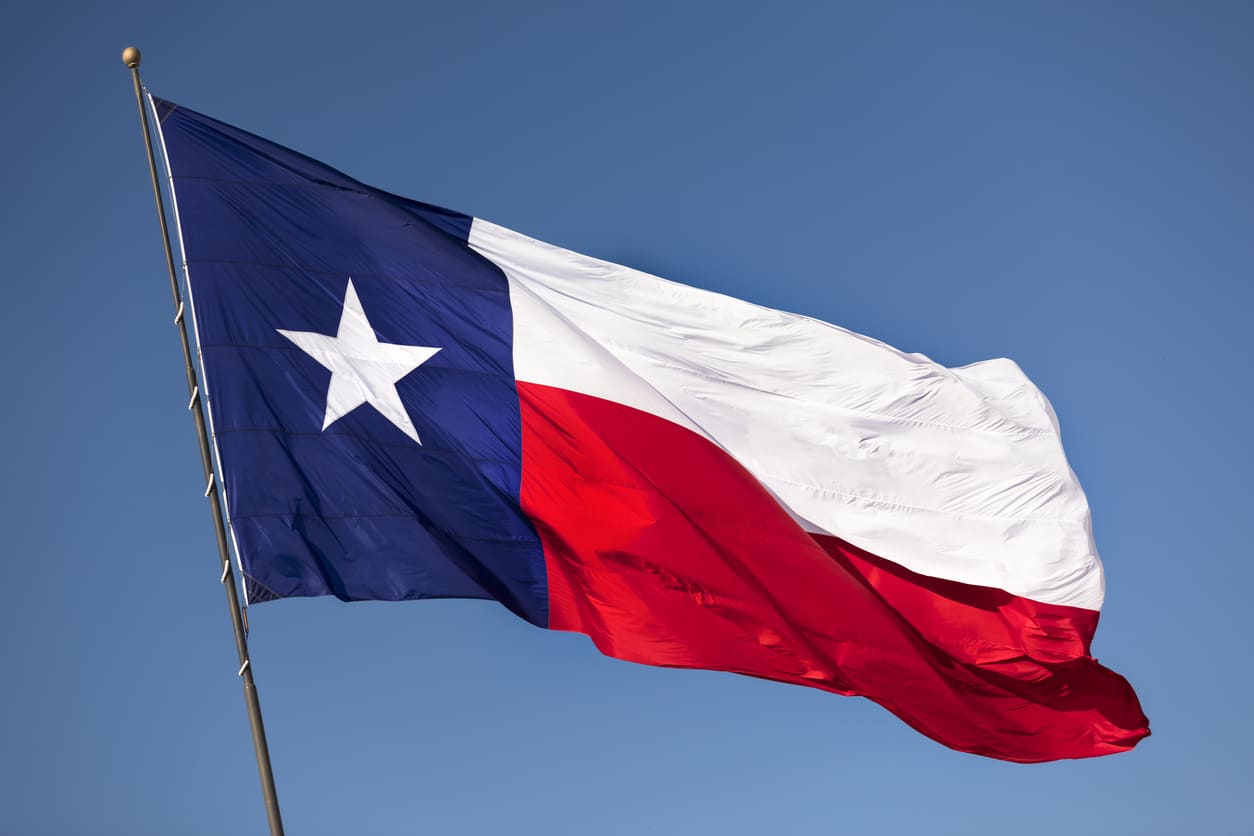 Lone Star Flag of Texas waving against a clear blue sky, symbolizing the state's pride and independence.