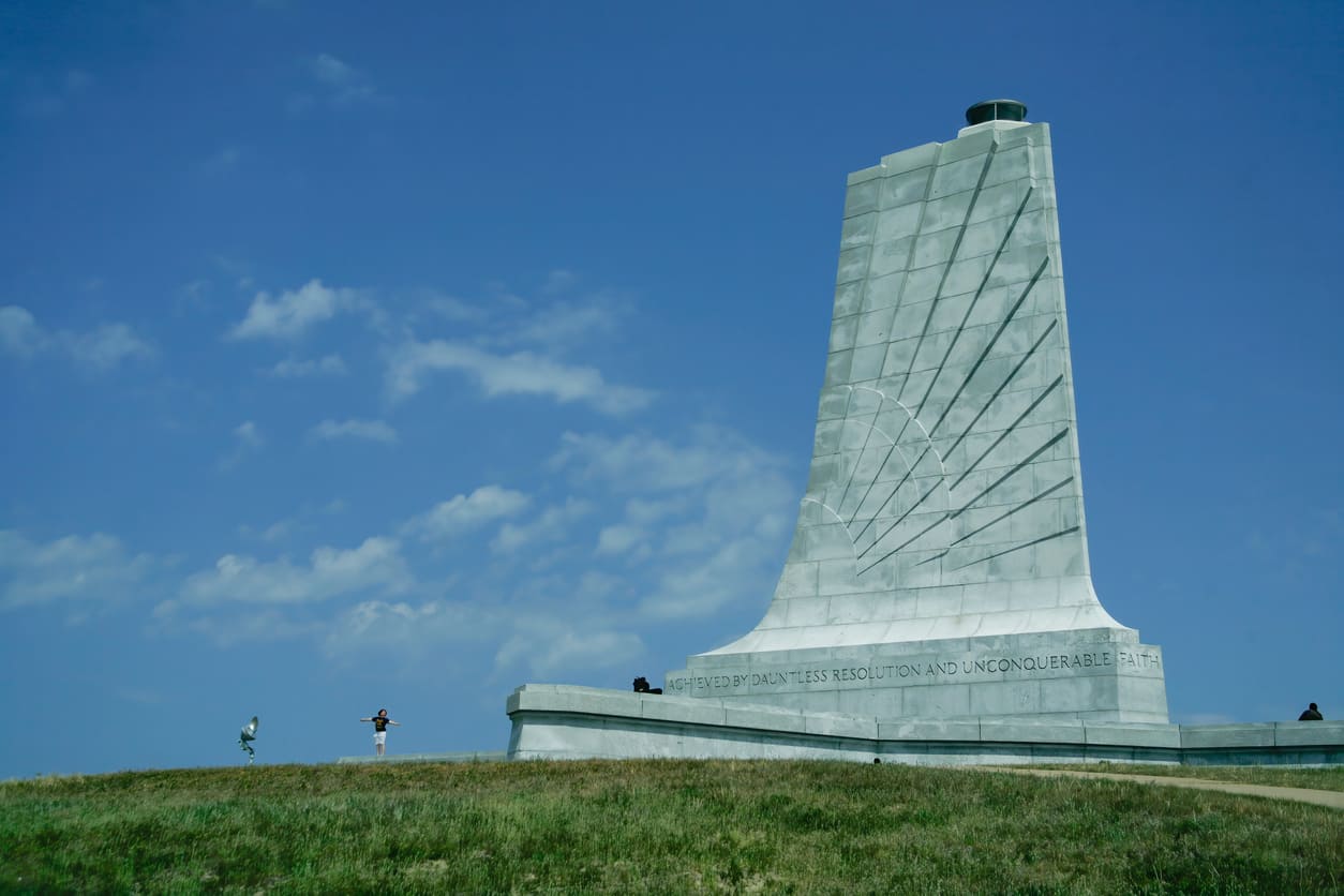 The Wright Brothers National Memorial honors their first flight, standing tall under a clear blue sky in Kitty Hawk, North Carolina.